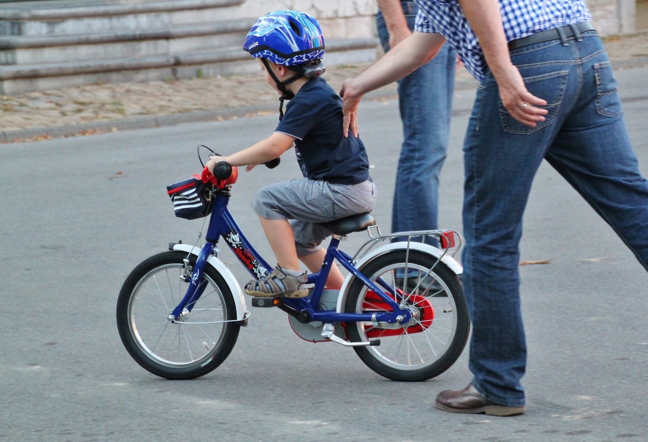 Eltern schieben Kind auf einem Rad